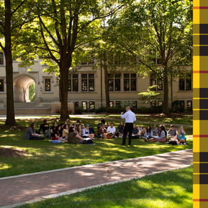 Students sitting outside on the lawn in front of Kauke Hall with a professor teaching