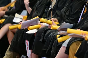 Graduates seated holding diploma