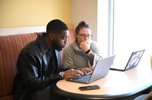 People sitting at a table looking at laptops